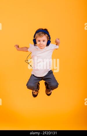 Portrait von glücklichen kleinen Jungen auf gelbem Hintergrund im Studio Stockfoto