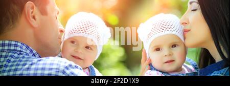 Frohe Familie. Vater und Mutter küssen und halten kleine Tochter Baby Mädchen im Freien am Sommertag, verschwommen grünen Hintergrund. Stockfoto