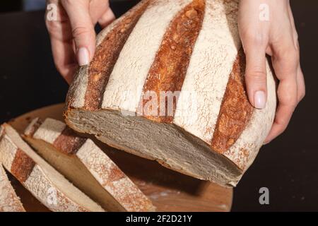 Weibliche Hände halten frisch gebackenes Brot. Hausgemachtes Backen. Stockfoto