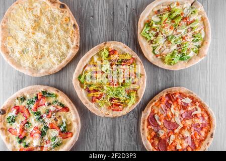 Auswahl an Pizza mit Fleisch, Salami, Prosciutto, Tomaten, Dorlu Käse, Mozzarella, Parmesan, Salat, Spinat, roter Fisch auf Holzbrettern. Vier Chee Stockfoto