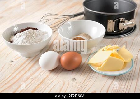 Zutaten für einen Kuchen wie Mehl, Eier, Butter und Zucker auf einem Holztisch, Backen zu Hause Konzept, Kopierraum, ausgewählter Fokus, enge Schärfentiefe Stockfoto