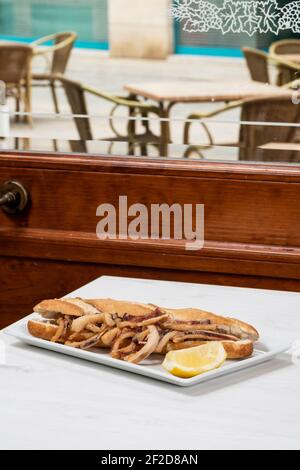 Calamari Sandwich mit einer Zitronenscheibe auf einem Tisch in Ein Restaurant Stockfoto