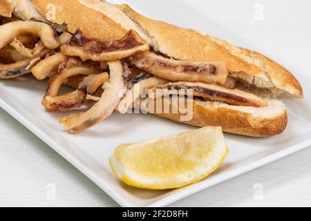 Calamari Sandwich mit einer Zitronenscheibe auf einem Tisch in Ein Restaurant Stockfoto