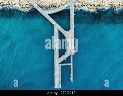 Luftaufnahme von oben auf dem hölzernen Pier im Limassol Molos Park und blauer Meeresoberfläche. Stockfoto