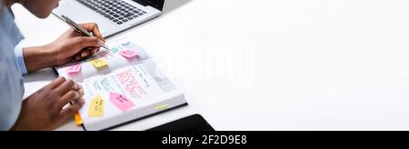 Afroamerikanische Frau, Die Am Schreibtisch In Den Kalender Schaut Stockfoto