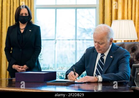 Washington, Vereinigte Staaten Von Amerika. März 2021, 11th. US-Präsident Joe Biden unterschreibt den amerikanischen Rettungsplan, während Vizepräsident Kamala Harris im Oval Office das Weiße Haus am 11. März 2021 in Washington, DC sieht Kredit: Planetpix/Alamy Live News Stockfoto