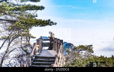 Der unspezifische Mann, der darauf wartet, am Aussichtspunkt bei Sonnenaufgang auf dem Huangshan-Berg ein Foto zu machen, ist einer der UNESCO-Welterbeliste, Stockfoto