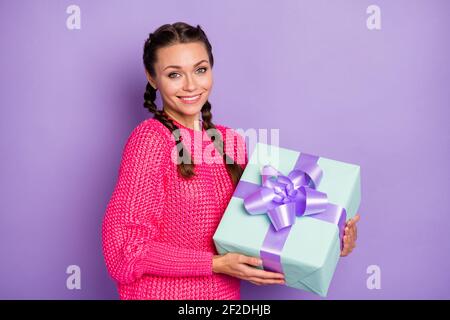 Foto von festlichen charmanten junge Frau halten Geschenk-Box erhalten Urlaub Geschenk isoliert auf violettem Hintergrund Stockfoto