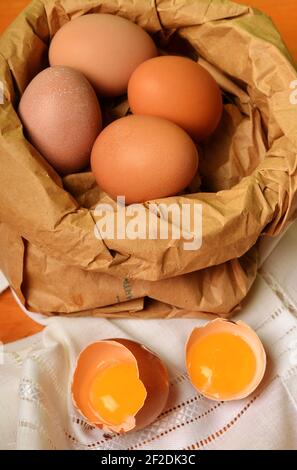 Ein Papier shopper voller Frische Eier anda gebrochen Ei auf dem hölzernen Tisch. Stockfoto