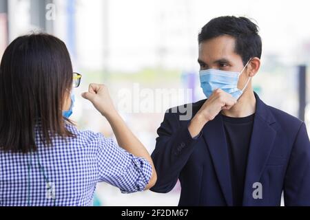 Zwei Personen tragen Gesichtsmaske schütteln Hand Ellenbogen schützen Coronavirus covid19 Stockfoto