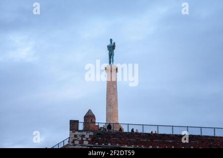 BELGRAD, SERBIEN - 12. DEZEMBER 2020: Touristen stehen vor der Victor-Statue auf der Festung Kalemegdan, während eines bewölkten Winternachmittages. Befindet sich in Stockfoto