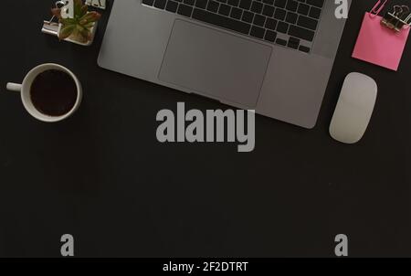 Schreibtisch mit Laptop und Notizpapier auf schwarzem Hintergrund, einschließlich Kopierbereich zum Hinzufügen von Text oder Grafiken. Stockfoto
