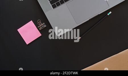 Schreibtisch mit Laptop und Notizpapier auf schwarzem Hintergrund, einschließlich Kopierbereich zum Hinzufügen von Text oder Grafiken. Stockfoto