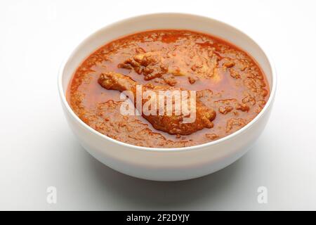 Chicken Curry oder Masala, würziges Chicken Curry aus frittierter Kokosnuss auf traditionelle Weise, angeordnet in einer weißen Keramikschale mit weißem Hintergrund, isola Stockfoto