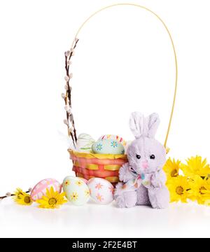 Osterkorb mit Blumen, Weidenzweigen, Eiern und niedlichem Hasen isoliert auf weißem Hintergrund. Frohe Ostern Stockfoto