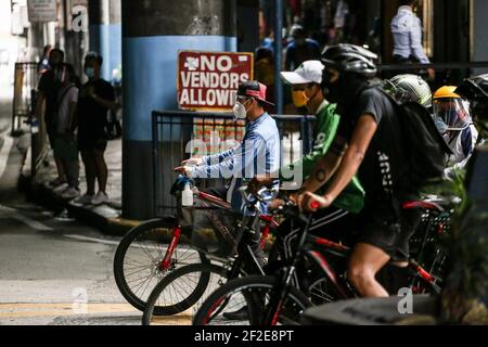 Ein Mann trägt eine Schutzmaske, während er mit dem Fahrrad eine Straße entlang fährt, da die COVID-19-Sperrbeschränkungen in Mandaluyong City, Metro Manila, Philippinen, lockern. Stockfoto