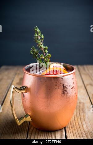 Cocktail aus roten Orangen in Kupferkrug (Variante des Moskauer Maultieres) auf dem Holzhintergrund. Selektiver Fokus. Geringe Schärfentiefe. Stockfoto