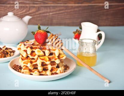 Frisch gebackene Waffeln mit Erdbeeren und Honig Stockfoto