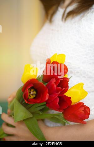 Weicher Fokus der anonymen weiblichen tragen Bündel von bunten frischen Tulpen während der Feiertagsfeier im Frühjahr. Stockfoto