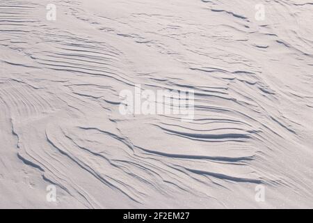 Zufällige Muster in funkelndem weißen Schnee, der vom Wind erzeugt wird Stockfoto