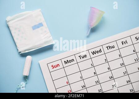 Kalender mit Tampons aus Baumwolle und Menstruationstasse. Frau kritische Tage und Hygieneschutz Stockfoto
