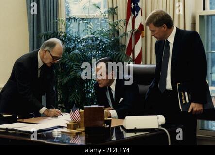 Präsident George H. W. Bush liest ein Dokument, wie General Brent Scowcroft Notationen macht und Vizepräsident Dan Quayle sich anschaut. Stockfoto