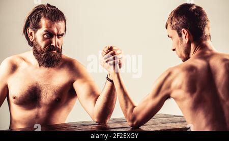 Arme ringen dünne Hand, großer starker Arm im Studio. Zwei Männerhände umklammten Arm Wrestling, stark und schwach, ungleiche Übereinstimmung Stockfoto
