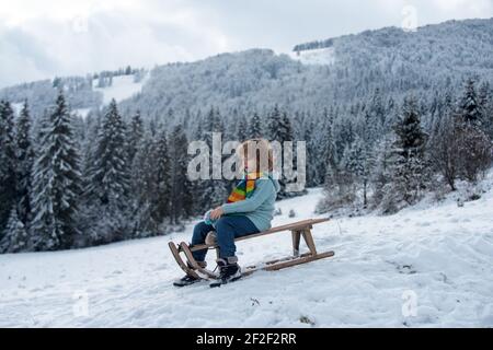 Lustige Kind im Schnee Fahrt auf Schlitten, Schlitten. Spiele im Winter im Freien. Happy Christmas Familienurlaubskonzept. Kinder Rodeln draußen im Winter. Stockfoto