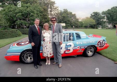 Präsident Ronald Reagan posiert mit Rennfahrer Richard Petty und seiner Frau Lynda vor Petty's Auto im Weißen Haus. Stockfoto