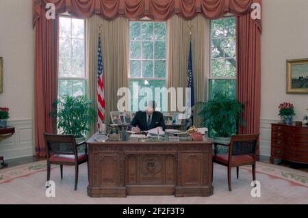 Präsident Ronald Reagan arbeitet an seinem Schreibtisch im Oval Office. Stockfoto