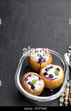 Gebackene Äpfel gefüllt mit Weichkäse und Heidelbeere auf schwarz Steinhintergrund Stockfoto