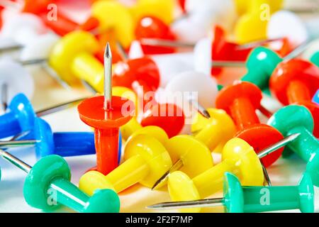 ? farbige Schreibwaren Tasten auf hellem Hintergrund ausgelegt. Nelken für die Ausbildung. Papier wird angehängt. Bürobedarf. Scharfer Stift zum Anbringen von Papier. Stockfoto