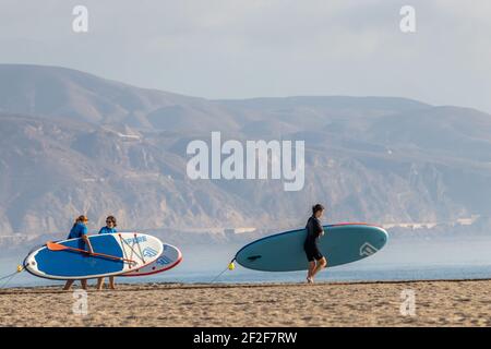 Almeria, Spanien. Oktober 10 202. Menschen, die mit ihren Paddelsurfen am Strand von Roquetas de Mar in Andalusien wandern Stockfoto