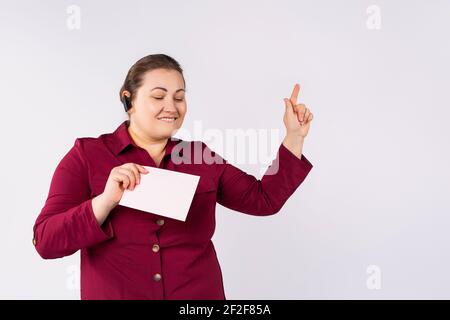Junge schöne blonde plus size Frau, trägt bluetooth-Headset, hält Verkauf leeres Banner über isolierten grauen Hintergrund, tanzen glücklich zeigen Stockfoto