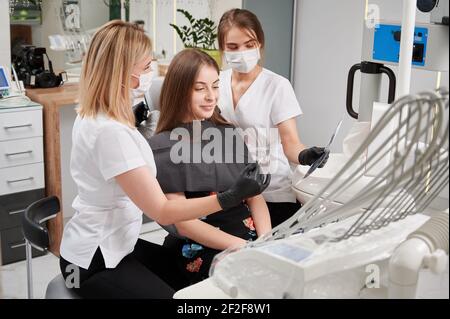 Zahnarzt und Assistent im Gespräch mit dem Patienten in der Zahnarztpraxis. Stockfoto