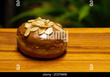 Ein Mini-Donut aus Mandel auf dem natürlichen Holztisch, in flachem Fokus Stockfoto