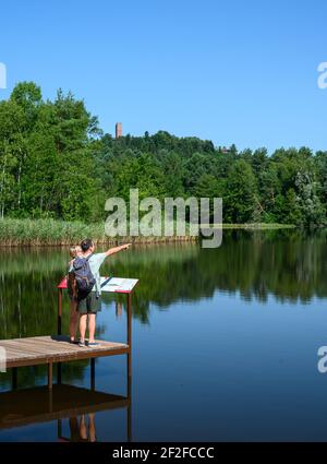 Zwei Reisende genießen Sommertag in der Natur. Am hölzernen Pier stehend und auf die Wasseroberfläche blickend. Stockfoto