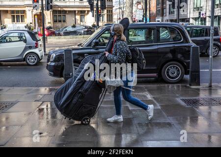 Music Student manövriert ihr Cello entlang der Marylebone Road in der Nähe der Royal Academy of Music, Central London, England, Großbritannien Stockfoto