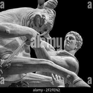Herkules kämpft gegen den kretischen Stier oder die Statue des gottes Mithras, der einen Stier tötet. Steinskulptur isoliert auf schwarzem Hintergrund Stockfoto