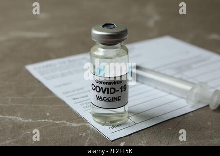 Konzept von Covid - 19 Impfung mit Impfstoff und Spritze Auf grauem texturiertem Hintergrund Stockfoto