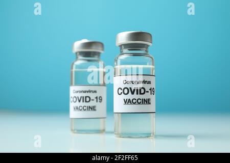 Fläschchen mit Covid - 19 Impfstoff vor blauem Hintergrund Stockfoto
