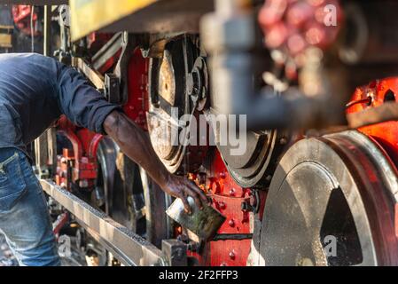 Lure Operator ölte die Räder der Lokomotive des Spielzeugzuges, Tamil Nadu, Indien Stockfoto