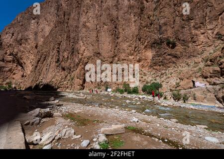 Todgha-Schlucht, Marokko - 13. April 2016: Die Menschen erfrischen sich am Fluss in der Todgha-Schlucht, in der Region des Hohen Atlasgebirges von Marokko. Stockfoto