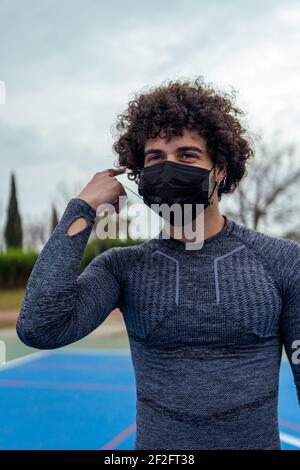 Ein vertikales Porträt eines jungen kaukasischen Athleten, der ein trägt Maske im Park Stockfoto