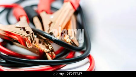 Nahaufnahme des roten und schwarzen Autobatterie-Jumper-Kabels, isoliert auf weißem Hintergrund. Ladekabel. Konzentrieren Sie sich auf Metall Stockfoto