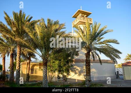 Eine kleine alte Moschee, umgeben von Dattelpalmen Stockfoto