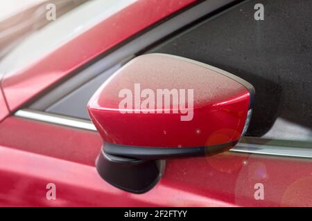 Transport Rückspiegel außen mit einer Schicht von Staub Nahaufnahme eines trockenen schmutzigen roten Auto bedeckt, niemand. Stockfoto