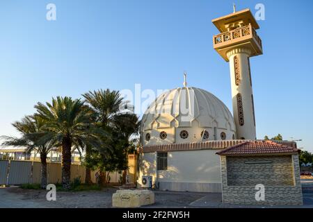 Eine kleine alte Moschee, umgeben von Dattelpalmen Stockfoto