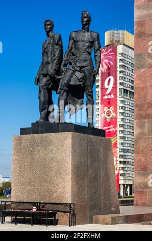 Sankt Petersburg, Russland - 05. Mai 2016: Statuen eines Arbeiters und eines Soldaten auf einem Sockel im Denkmal für die Verteidiger von Leningrad und eine rote banne Stockfoto