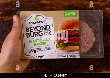 rom, italien - 10 märz 2021:Hand halten über Fleisch Veggie pflanzenbasierte Burger auf Holzhintergrund mit Verpackung. Pflanzenbasierte vegetarische Ernährung Stockfoto